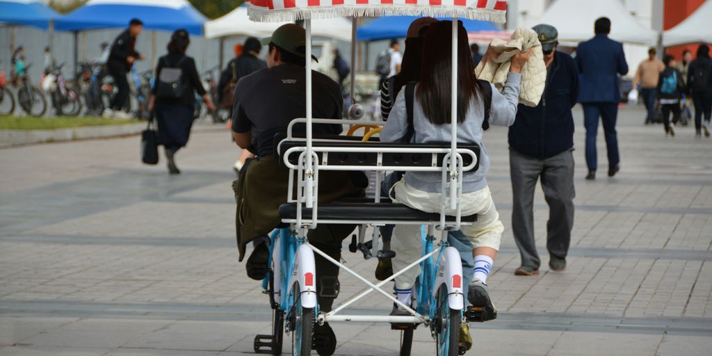 a man and a woman riding a bike with a canopy