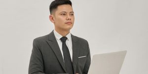 A businessman is holding a laptop and looking up.
