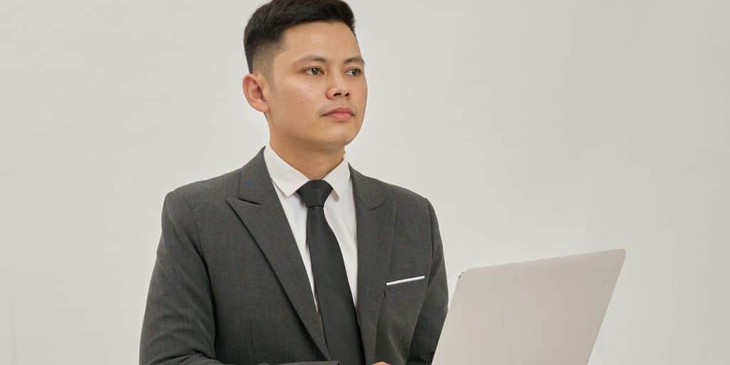 A businessman is holding a laptop and looking up.