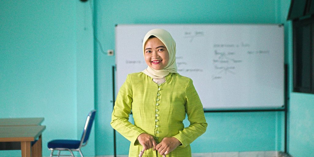 A smiling woman stands in front of a whiteboard.