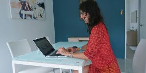 Woman works on laptop at a table.