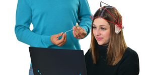 a man standing next to a woman using a laptop